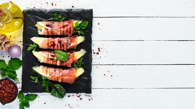 Prosciutto au melon sur une assiette en pierre Apéritif italien traditionnel Vue de dessus Espace de copie gratuit