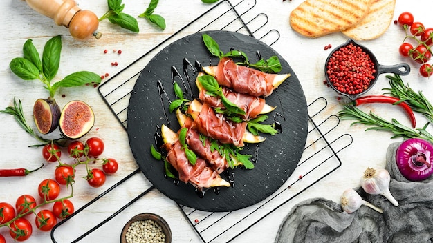 Prosciutto aux poires et basilic sur une plaque de pierre noire antipasto italien Jamon Vue de dessus