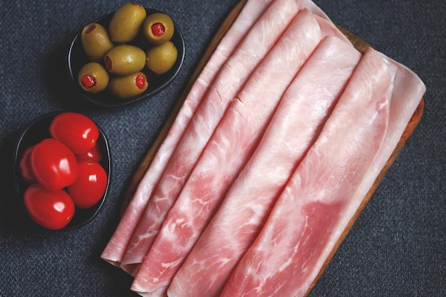 Prosciutto cotto sur une planche de bois avec olives et tomates cerises apéritif italien