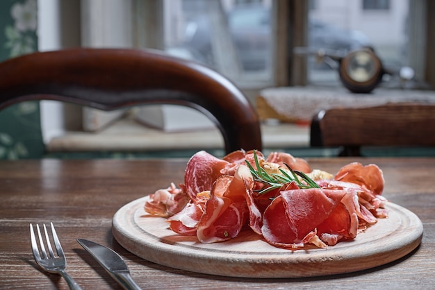 prosciutto sur planche à découper en bois. sur fond de table en bois.