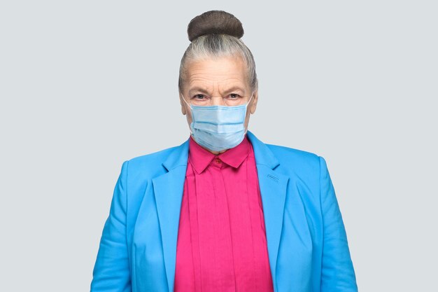 Protection contre les maladies contagieuses, coronavirus. Femme âgée avec masque hygiénique pour prévenir les infections, les maladies respiratoires aéroportées telles que la grippe, Covid-19. studio intérieur tourné isolé, fond gris
