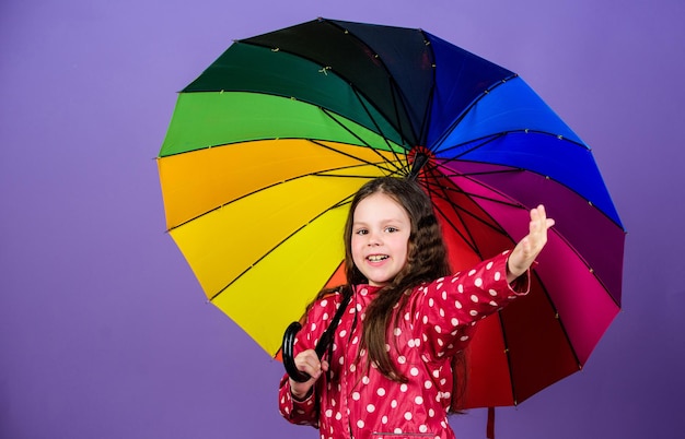 Protection contre la pluie. Arc-en-ciel. mode d'automne. heureuse petite fille avec parapluie coloré. enfant hipster joyeux d'humeur positive. Petite fille en imperméable. Prendre le temps de se reposer.