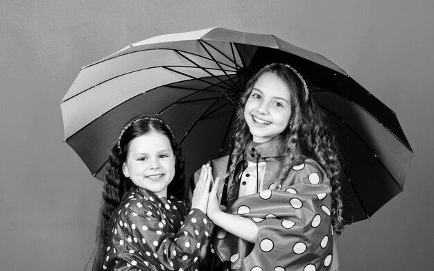 Protection contre la pluie Mode automne arc-en-ciel Petites filles heureuses avec un parapluie coloré Enfants hipster gais Liens familiaux de fraternité Petites filles en imperméable Tous les temps sont bons