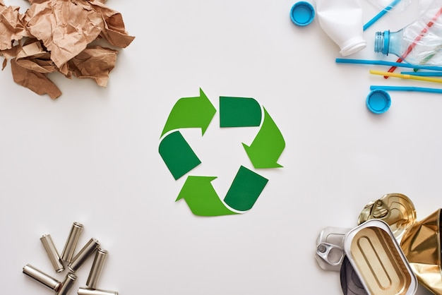 Protéger l'environnement. Différents types de déchets. Piles, cannettes, papier et plastique dans les coins avec regard recyclé au centre
