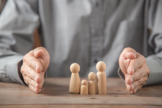 Protégez les mains de la poupée en bois de la famille pour la protection de la planification de l'assurance et la sécurité du concept d'assurance maladie familiale