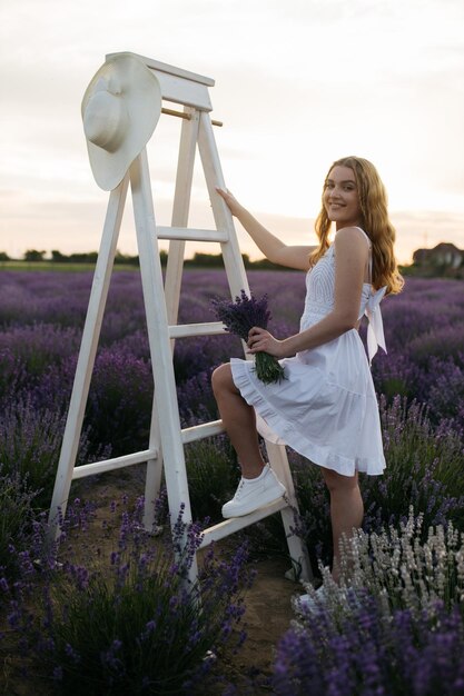 Provence France Une fille en robe blanche marchant à travers les champs de lavande au coucher du soleil