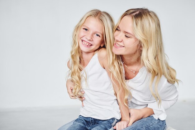 Proximité des gens. Mère avec sa fille ensemble en studio avec fond blanc.