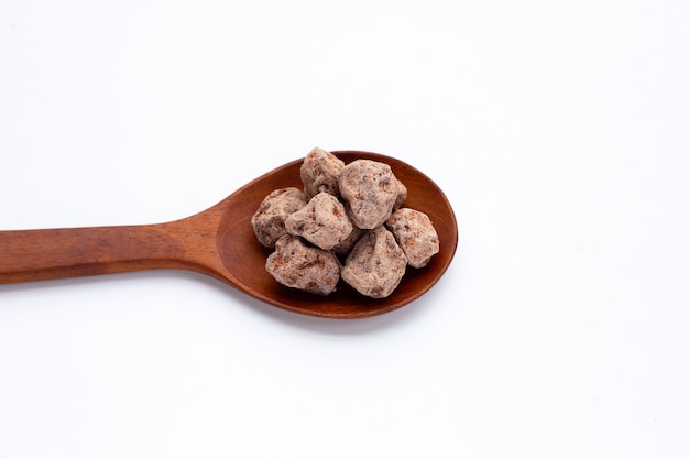 Prune chinoise salée séchée dans une cuillère en bois sur fond blanc.