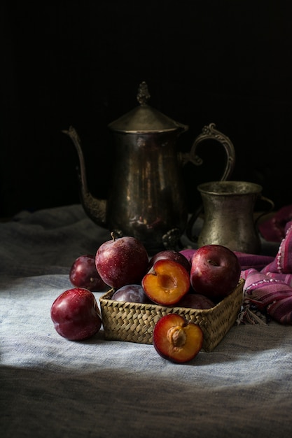 Prune fraîche. Récolte d&#39;automne. Prunes rouges. serviette de table, bouilloire et verre vintage. Articles en bronze Vege