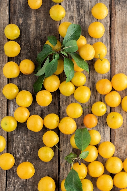 Prune jaune vif sur un fond en bois, vue du dessus.