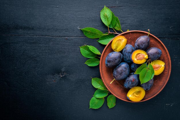 Prunes aux feuilles vertes Sur un fond en bois Vue de dessus Espace libre pour le texte