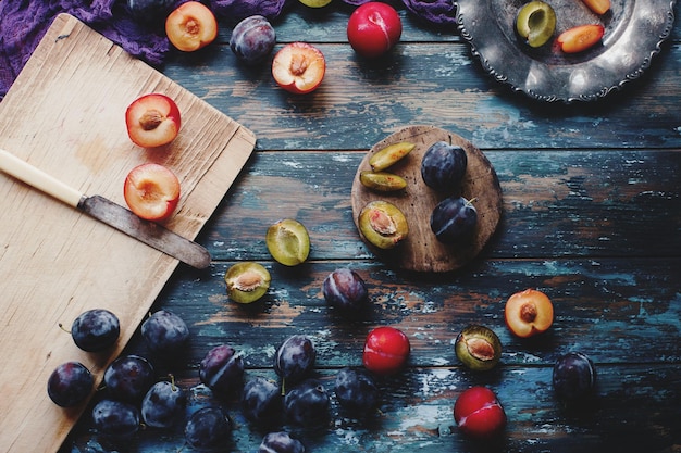 Prunes biologiques fraîches et tranches de prunes sur planche de bois et table en bois rustique récolte d'automne fruits de saison mode de vie sain vue de dessus mise au point sélective