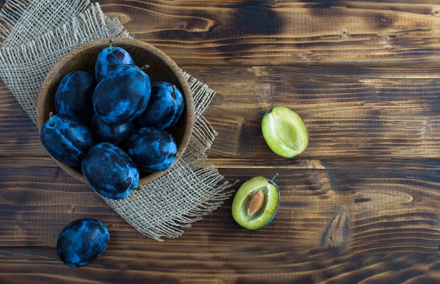 Prunes bleues mûres dans le bol sur le fond en bois rustique Vue de dessus Espace de copie