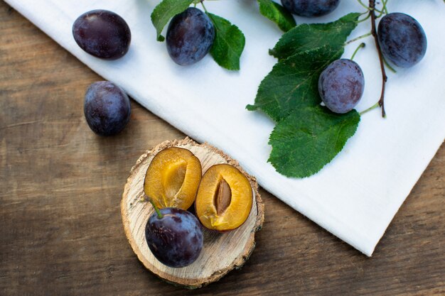 Prunes bleues mûres sur une texture en bois