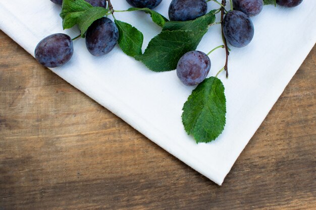 Prunes bleues mûres sur une texture en bois