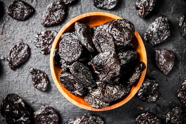 Des prunes dans une assiette en bois sur la table