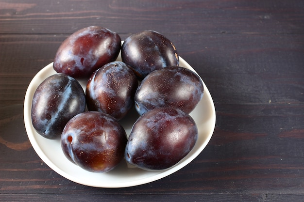 Photo prunes dans une assiette sur une table sombre