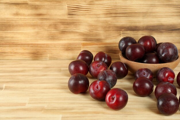 Prunes dans un bol en bois sur une table en bois.