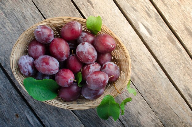 Prunes dans un panier en osier sur fond de bois ancien