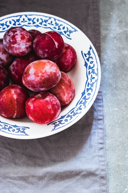 Prunes de différentes variétés dans une assiette en céramique blanche avec un motif