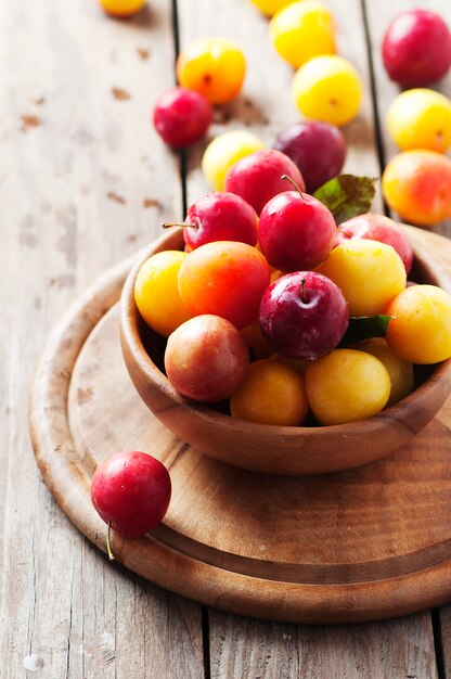 Prunes douces jaunes et rouges sur la table en bois