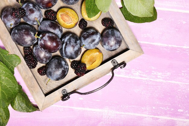 Photo prunes douces mûres sur plateau sur table en bois rose