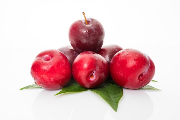 Prunes avec feuilles de prunier isolé sur fond blanc