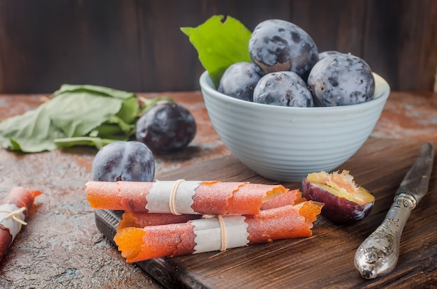 Prunes fraîchement cueillies dans un bol en poterie et pastille de prunes dans le noir