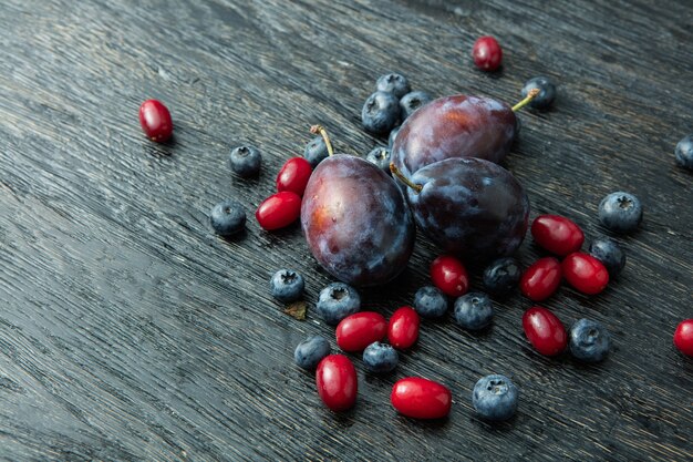 Prunes fraîches et baies sur une table en bois sombre