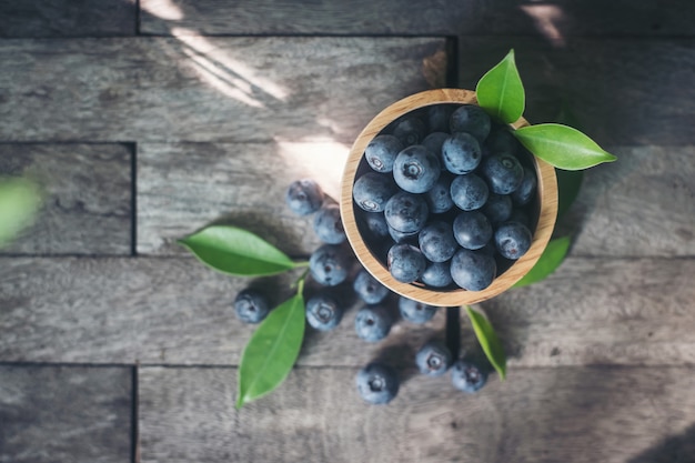 Prunes fraîches dans un bol en bois sur le vieux fond en bois