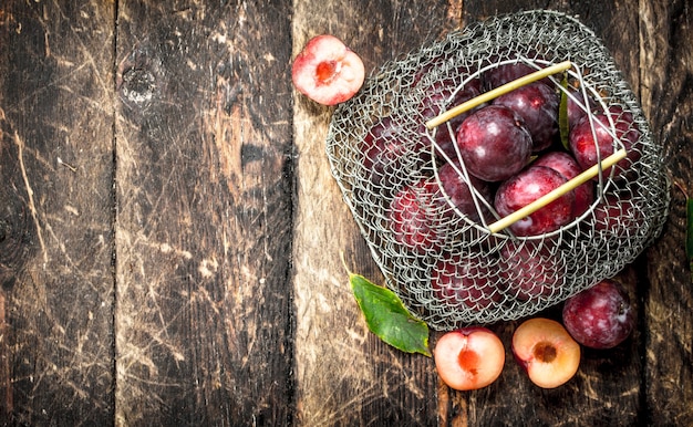 Prunes Fraîches Dans Un Sac En Filet. Sur Un Fond En Bois.