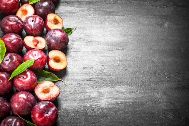 Prunes fraîches avec des feuilles. Sur le tableau noir.