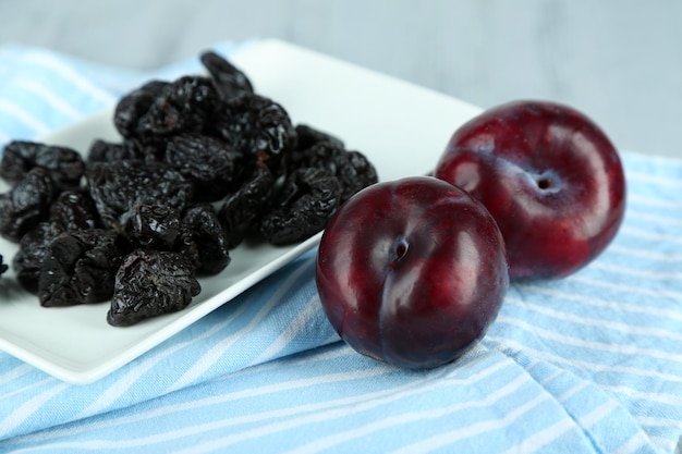 Prunes fraîches et séchées sur serviette sur fond de bois