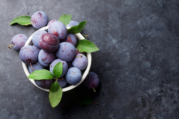 Prunes de jardin dans un bol sur une table en pierre