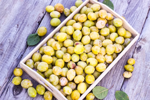 Prunes jaunes fraîches Fruits mûrs dans une boîte en bois sur fond de planches rugueuses à l'extérieur