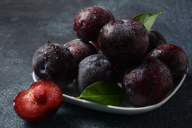 Prunes juteuses dans une assiette. Prunes bleues fraîches.