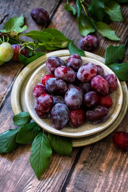 Prunes juteuses mûres dans un bol sur un fond en bois