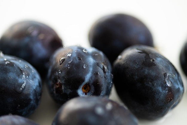 Prunes juteuses mûres sur fond blanc