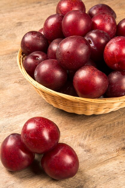 Prunes lumineuses fraîches dans le bol à bord. Fruits frais.