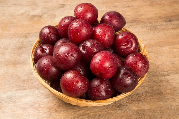 Prunes lumineuses fraîches dans le bol à bord. Fruits frais.