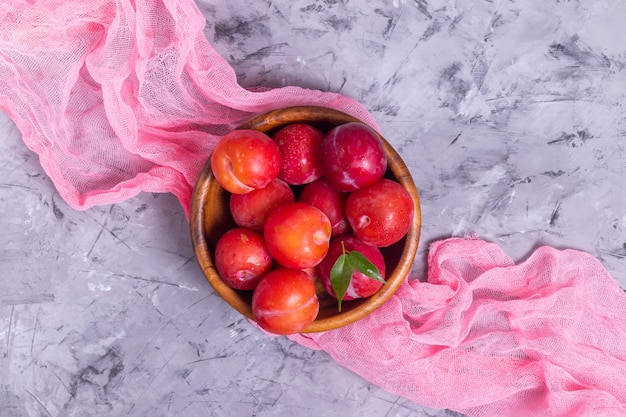 Prunes mûres dans une assiette en bois avec de la rosée avec une serviette rose