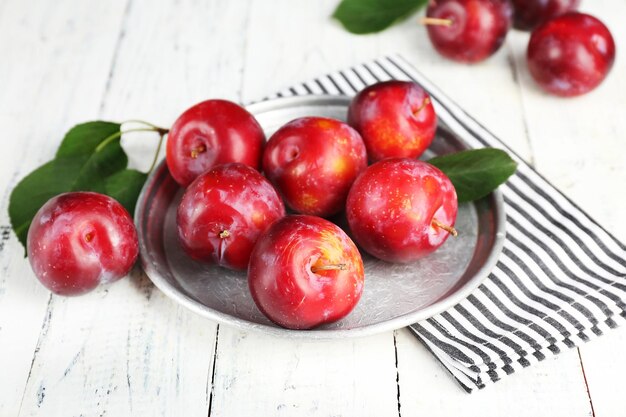 Prunes mûres dans une plaque de métal sur une table en bois agrandi