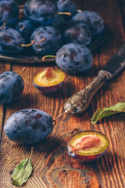 Prunes mûres avec feuilles et couteau