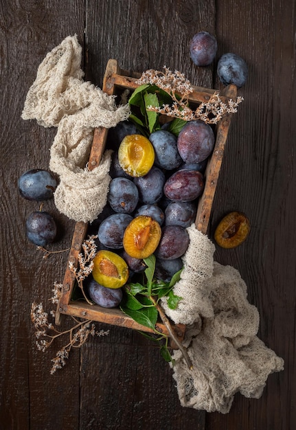 prunes noires mûres sur une table marron en bois