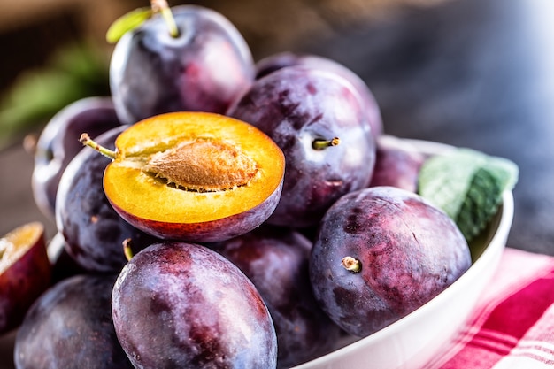 Prunes. Prunes juteuses fraîches dans un bol sur une planche en bois ou en béton.