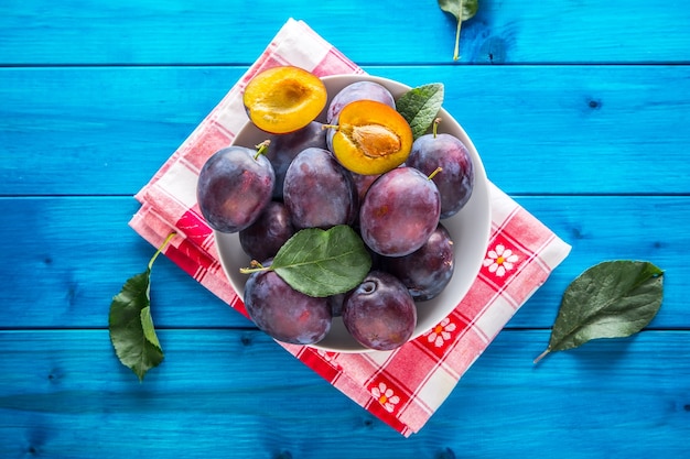 Prunes. Prunes juteuses fraîches dans un bol sur une planche en bois ou en béton.