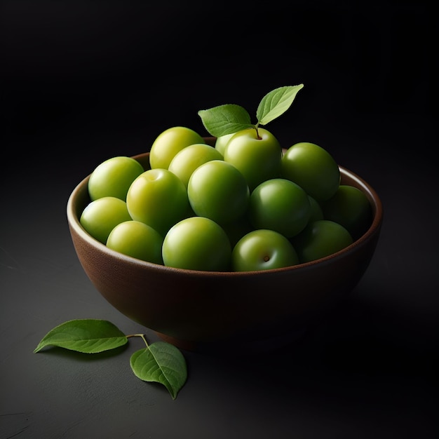 Des prunes vertes dans un bol avec des feuilles sur une surface noire