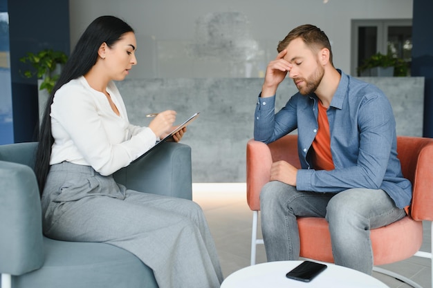 Psychologie thérapie mentale et concept de personnes femme psychologue parlant à un jeune homme triste patient lors d'une séance de psychothérapie