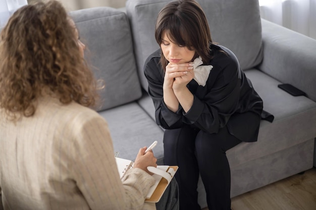 Psychologue consultant une patiente prenant des notes assise sur un canapé confortable