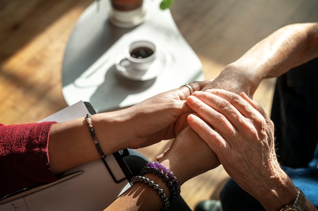 Psychologue féminine tenant les mains d'un patient âgé